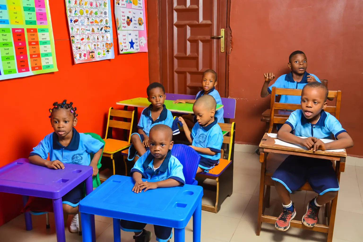 Young pupils seated at colourful desks in a school classroom