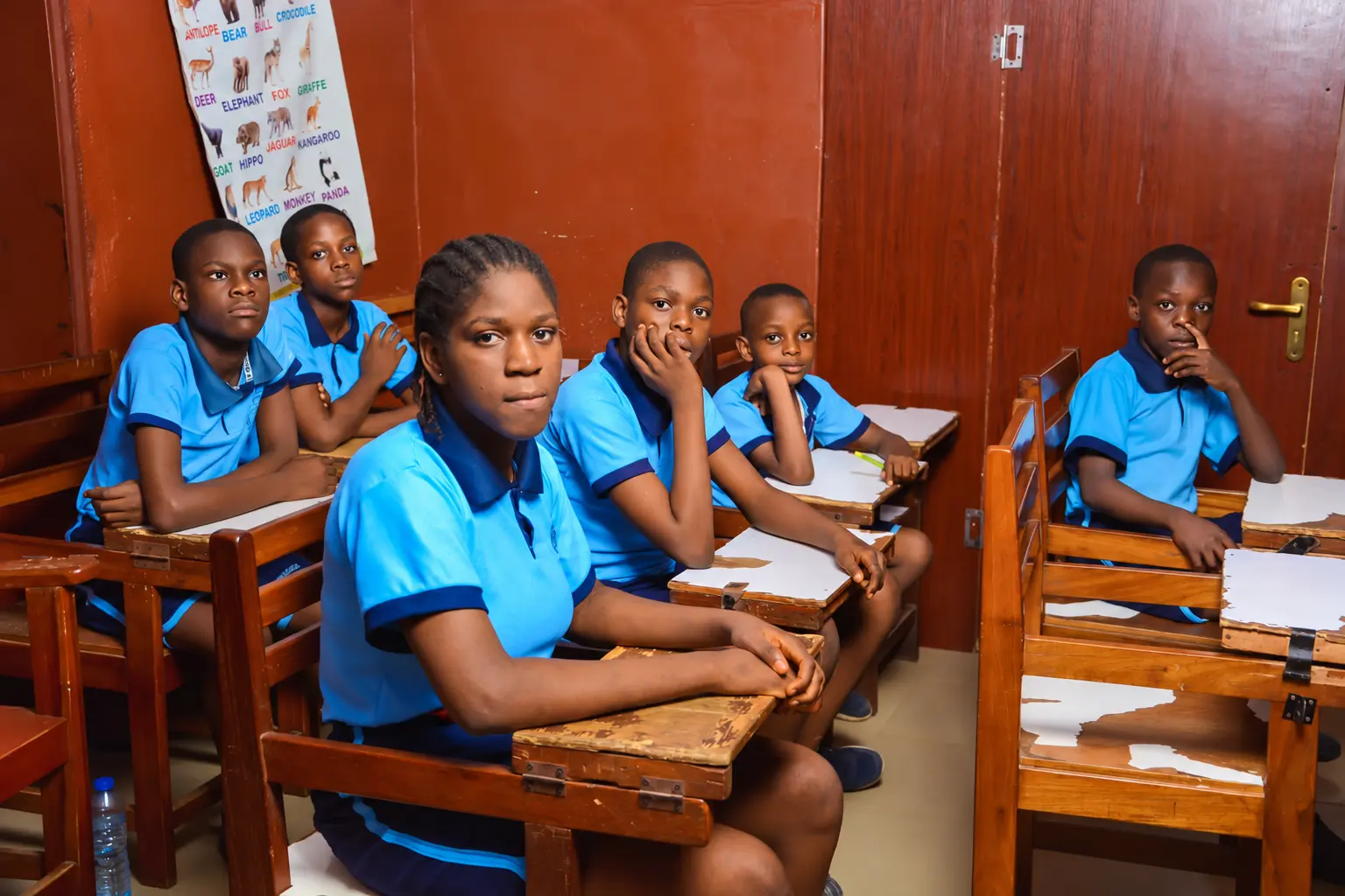 Pupils in blue uniforms seated together in a classroom